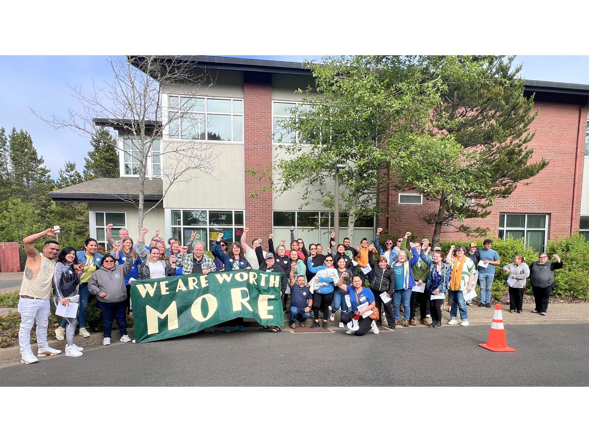 People holding sign that says "We are worth MORE"